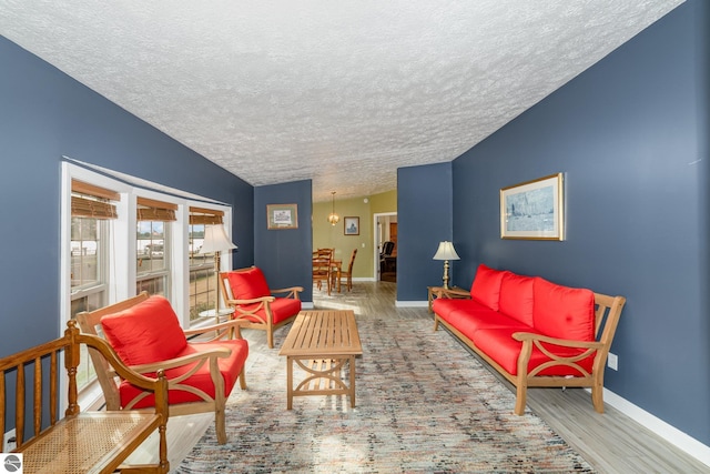 living area with lofted ceiling, a textured ceiling, baseboards, and wood finished floors