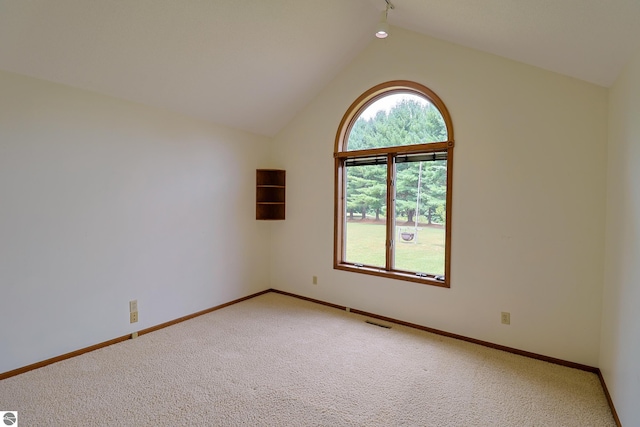 unfurnished room featuring lofted ceiling, light colored carpet, visible vents, and baseboards