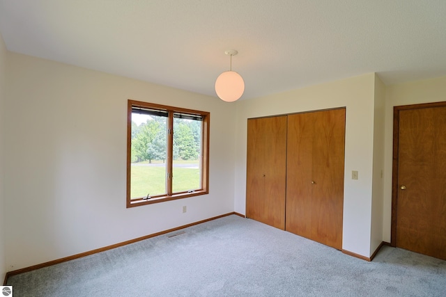 unfurnished bedroom with light carpet and a closet