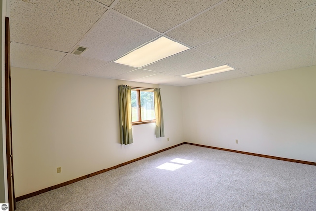 carpeted empty room featuring a drop ceiling, visible vents, and baseboards