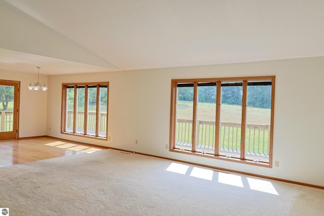 unfurnished room featuring baseboards, light carpet, lofted ceiling, and a chandelier