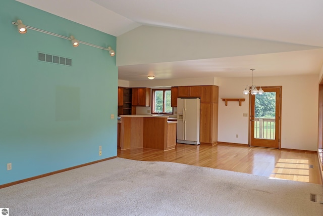 unfurnished living room featuring lofted ceiling, light hardwood / wood-style flooring, and a notable chandelier