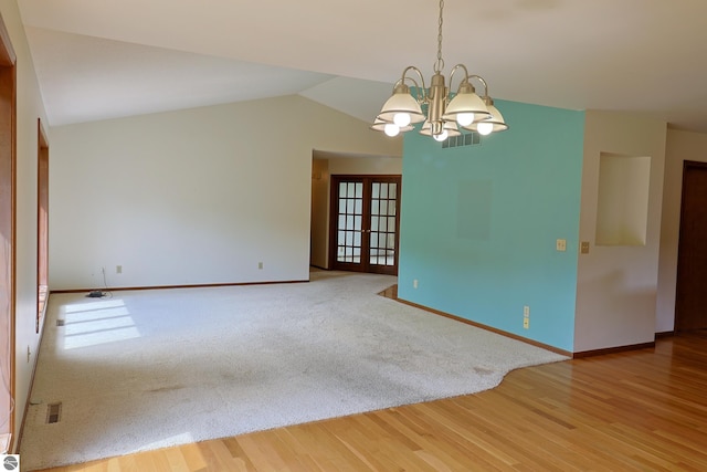 unfurnished room with french doors, lofted ceiling, a chandelier, and hardwood / wood-style floors