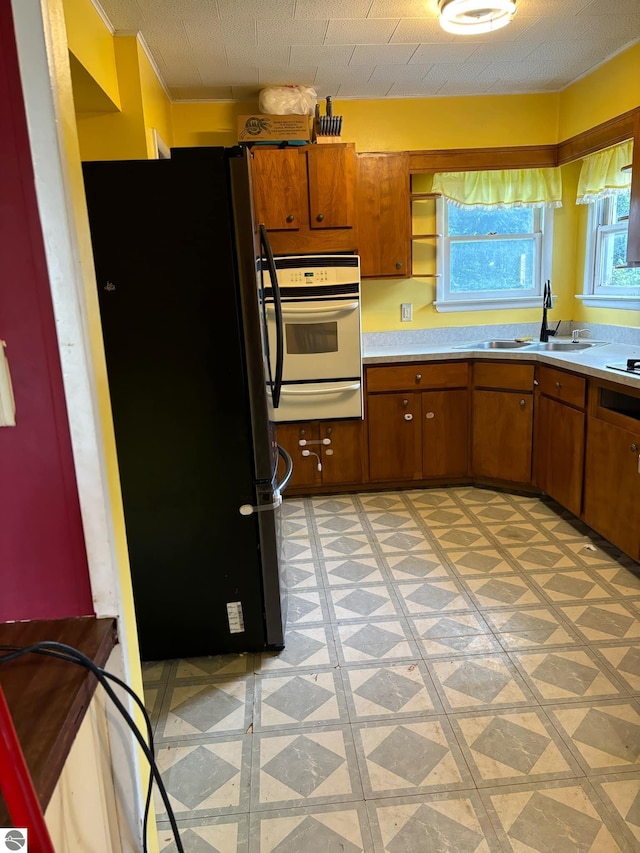 kitchen with black refrigerator, a textured ceiling, oven, and sink