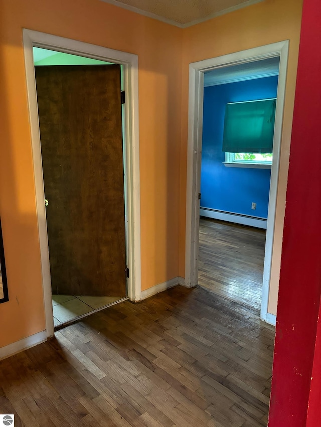 corridor featuring crown molding, wood-type flooring, and baseboard heating