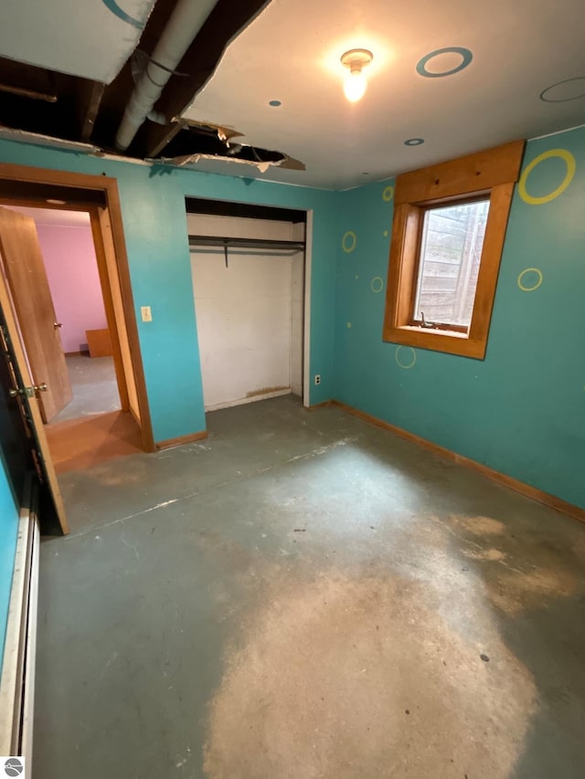 unfurnished bedroom featuring concrete floors and a closet