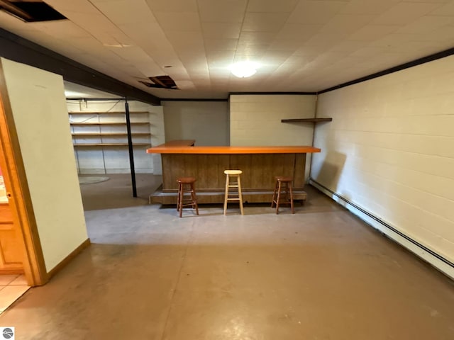 basement with a baseboard radiator and indoor bar