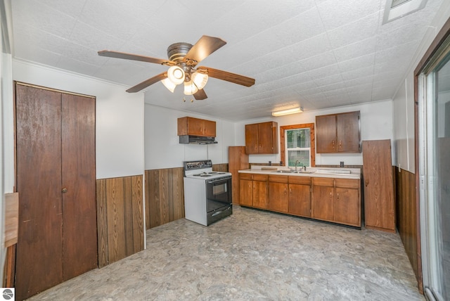 kitchen featuring wood walls, sink, ceiling fan, and white electric range oven