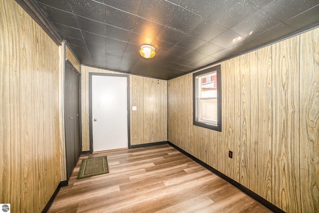 unfurnished room with light wood-type flooring and wooden walls