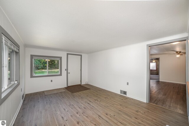 unfurnished living room featuring ceiling fan, wood-type flooring, and a textured ceiling