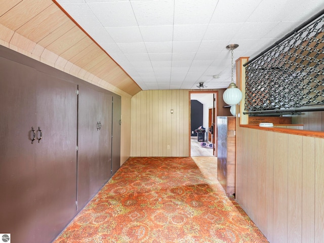 corridor featuring light carpet and wooden walls