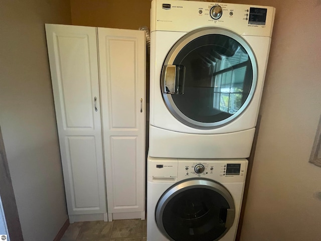 laundry area with cabinets and stacked washer and clothes dryer