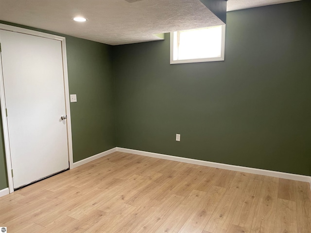 basement with light hardwood / wood-style floors and a textured ceiling