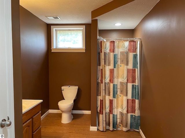 bathroom featuring toilet, hardwood / wood-style floors, a shower with shower curtain, vanity, and a textured ceiling