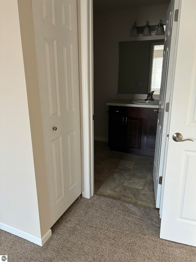 hallway with dark colored carpet and sink