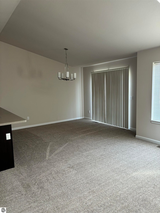 spare room featuring carpet flooring and a chandelier