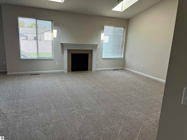 unfurnished living room with light carpet, a skylight, and a tile fireplace