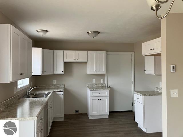 kitchen with dark wood-type flooring, sink, and white cabinets