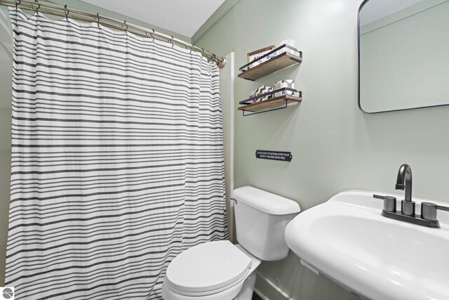 bathroom featuring toilet, a shower with shower curtain, and sink