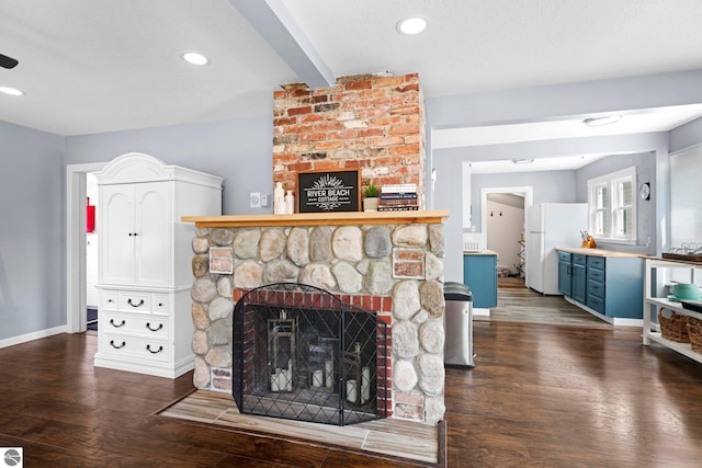 living room with dark wood-type flooring, a textured ceiling, and a stone fireplace