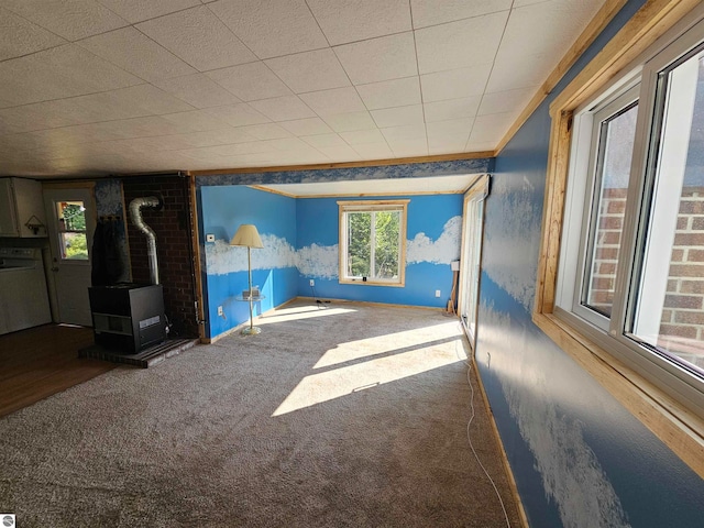 unfurnished living room featuring a wood stove and carpet