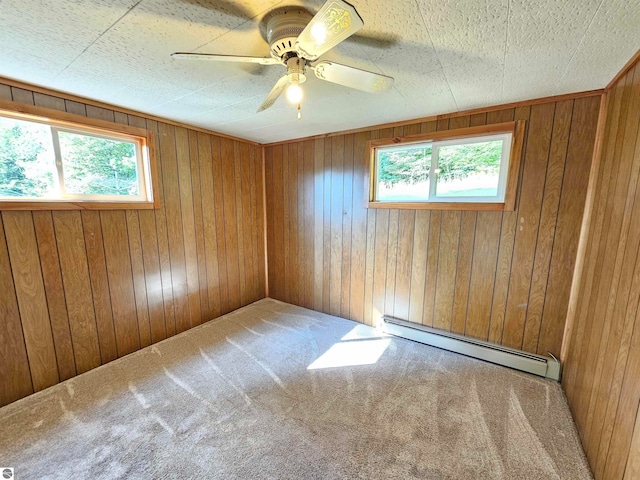 spare room featuring a baseboard radiator, ceiling fan, carpet, and wooden walls