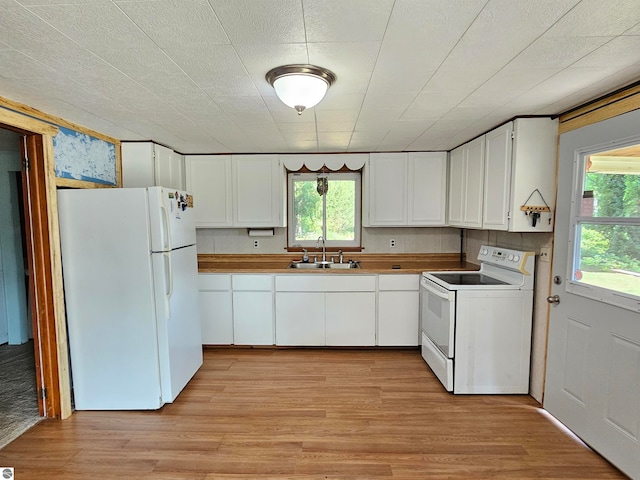 kitchen with white cabinets, white appliances, and light hardwood / wood-style flooring