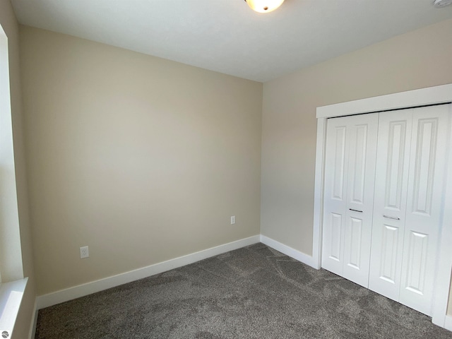 unfurnished bedroom featuring a closet and dark carpet