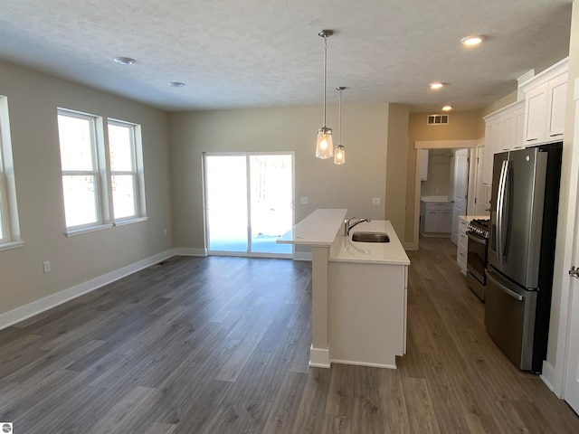 kitchen featuring a wealth of natural light, white cabinetry, stainless steel appliances, and an island with sink