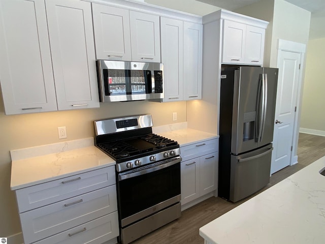 kitchen with appliances with stainless steel finishes, white cabinetry, and dark hardwood / wood-style flooring