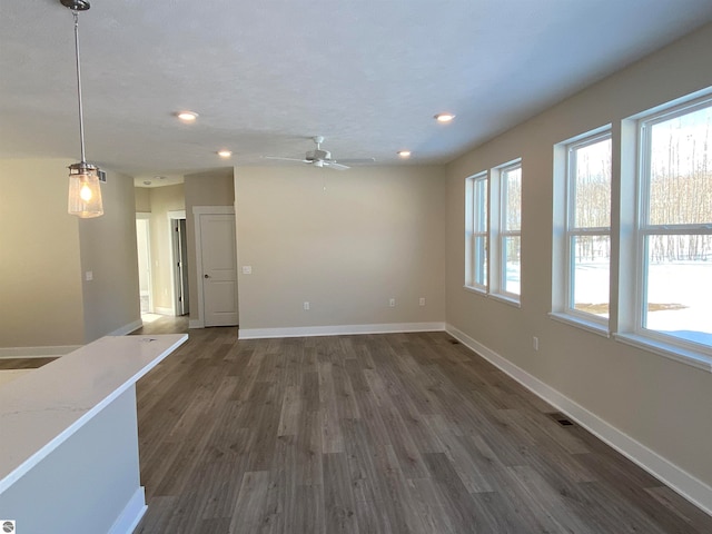 unfurnished living room featuring ceiling fan and dark hardwood / wood-style flooring