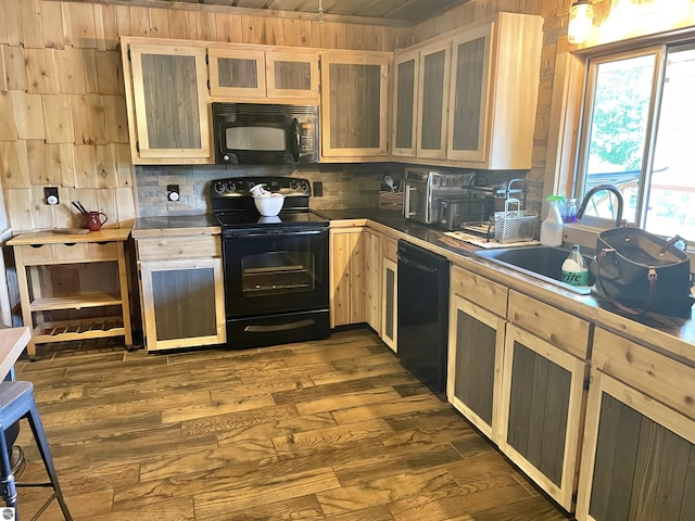 kitchen featuring backsplash, dark wood-type flooring, glass insert cabinets, a sink, and black appliances