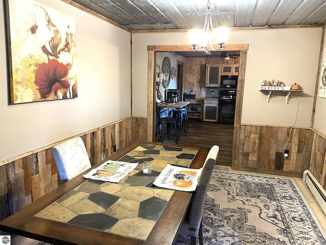 dining area with a baseboard radiator, a notable chandelier, wooden walls, wood finished floors, and wainscoting