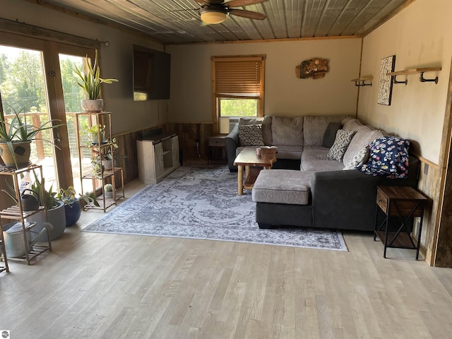 living room with a wainscoted wall, wooden ceiling, light wood-style flooring, and a ceiling fan