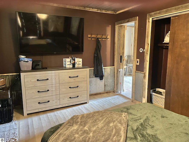 bedroom with a wainscoted wall, a closet, and light wood-type flooring