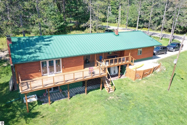 back of house with a lawn, a chimney, stairway, metal roof, and a standing seam roof