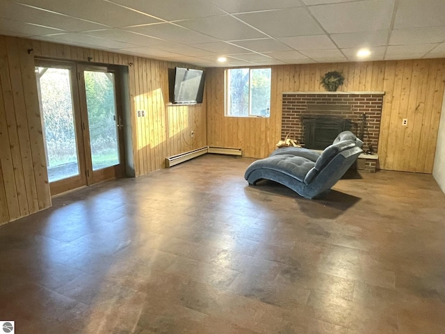 living area with wooden walls, a baseboard radiator, tile patterned floors, a paneled ceiling, and a fireplace