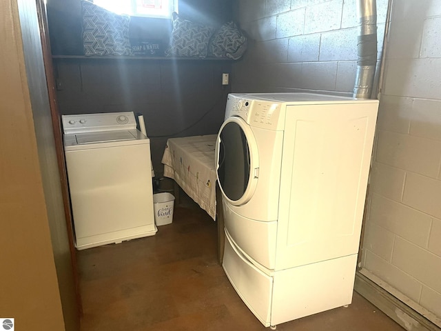 clothes washing area with concrete block wall, laundry area, and washer and clothes dryer