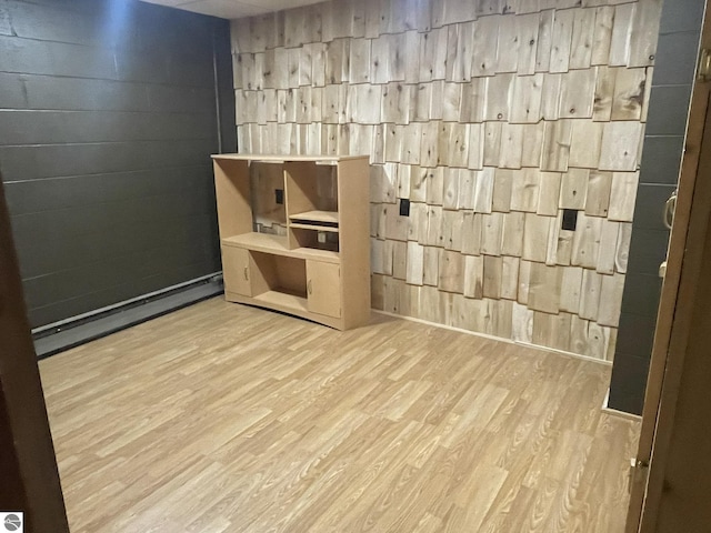 unfurnished room featuring a baseboard heating unit, wood walls, and wood finished floors