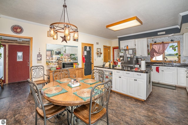 dining space featuring a notable chandelier, sink, crown molding, and a textured ceiling