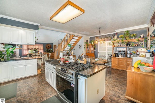 kitchen with stainless steel gas stove, crown molding, white cabinetry, a center island, and vaulted ceiling