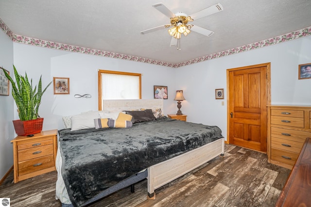 bedroom with dark wood-type flooring, a textured ceiling, and ceiling fan