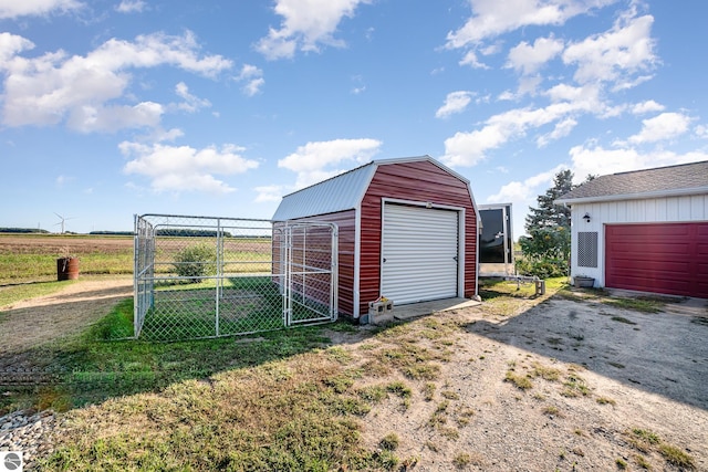 view of outbuilding with a yard, a garage, and a rural view