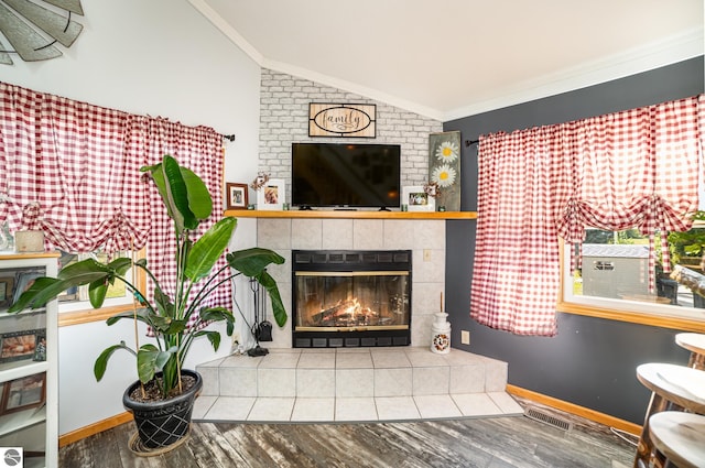 living room featuring vaulted ceiling, ornamental molding, hardwood / wood-style flooring, and a fireplace