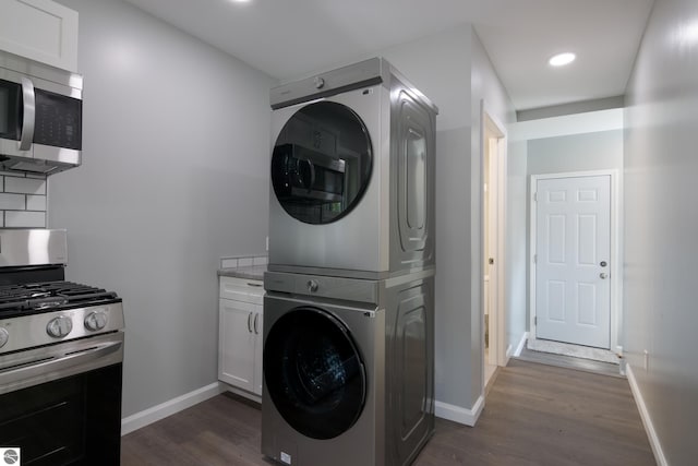 clothes washing area featuring stacked washer and clothes dryer and dark hardwood / wood-style flooring