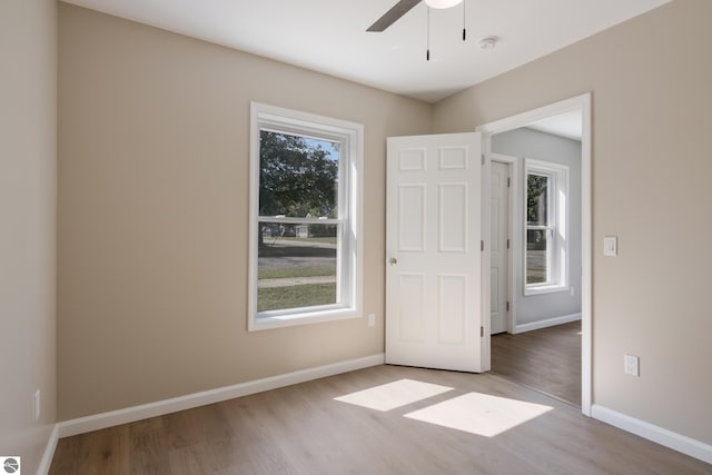 unfurnished room featuring plenty of natural light, ceiling fan, and hardwood / wood-style floors