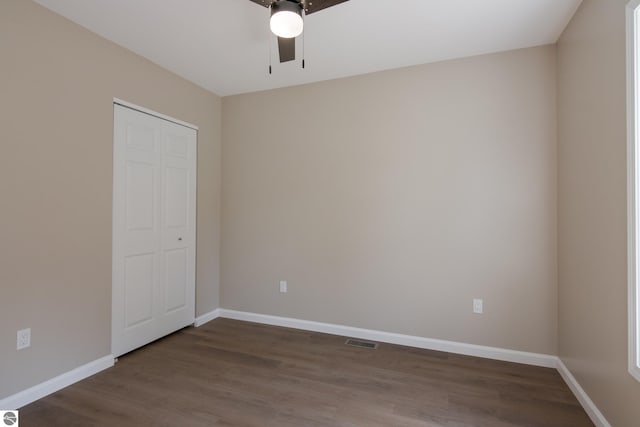 unfurnished bedroom with ceiling fan, dark hardwood / wood-style floors, and a closet