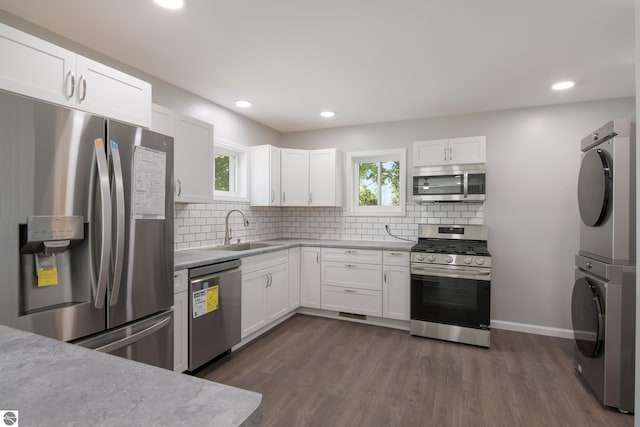 kitchen featuring plenty of natural light, sink, stainless steel appliances, and stacked washer and dryer