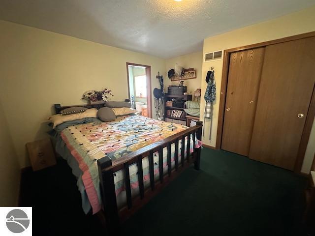 carpeted bedroom featuring visible vents, a closet, and a textured ceiling