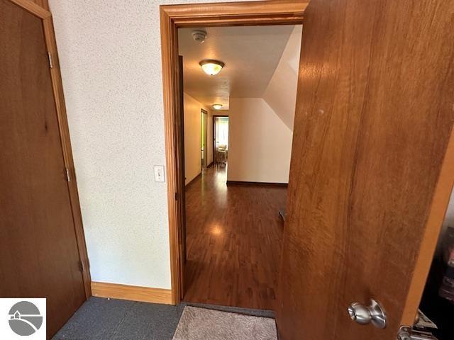 hall featuring dark hardwood / wood-style flooring and lofted ceiling